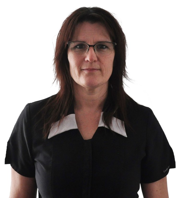 Sonia Simard en chemise de massage, elle porte des lunettes et sourit.