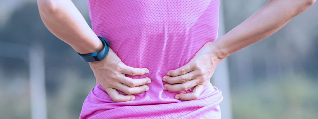 Femme qui se tient le dos avec les deux mains.